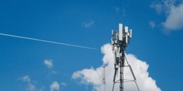 Cell tower against a bright blue sky with clouds