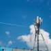 Cell tower against a bright blue sky with clouds