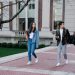 Group of young students walking on campus sidewalk on a bright day, showcasing casual university life.