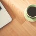 A coffee cup and laptop on a wooden desk, creating a cozy workspace vibe.