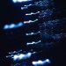 Dynamic abstract photograph of blue light patterns with a dark backdrop, creating a sense of motion and mystery.
