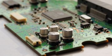 Detailed view of a green circuit board featuring capacitors and microchips.
