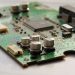 Detailed view of a green circuit board featuring capacitors and microchips.