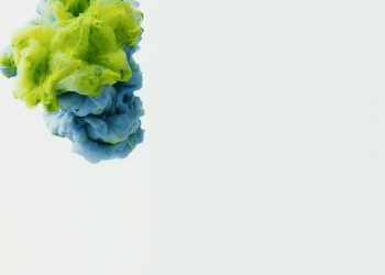 A vivid display of green and blue ink suspended in water, creating an artistic abstract scene.