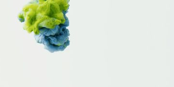 A vivid display of green and blue ink suspended in water, creating an artistic abstract scene.