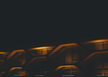 A modern building facade illuminated by neon lights, showcasing futuristic architectural design at night.