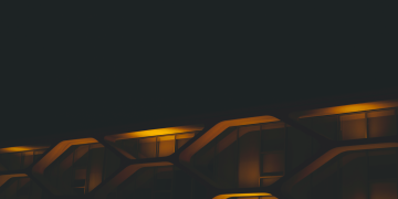 A modern building facade illuminated by neon lights, showcasing futuristic architectural design at night.