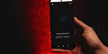A hand holds a smartphone displaying Grok 3 announcement against a red background.