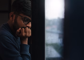 Contemplative man gazing out a rainy window, lost in thought.