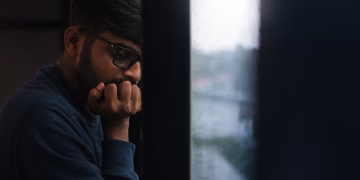 Contemplative man gazing out a rainy window, lost in thought.