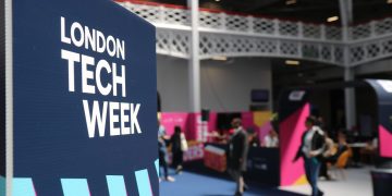 Vibrant indoor scene at London Tech Week with attendees and colorful displays.