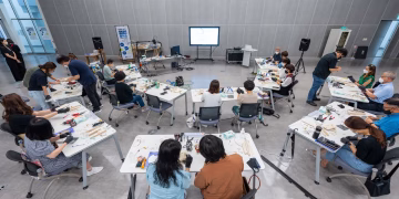 Overhead view of a hands-on classroom workshop with diverse students using hi-tech equipment.