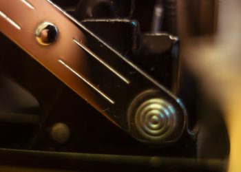 Close up of a metallic spring mechanism on black machinery.