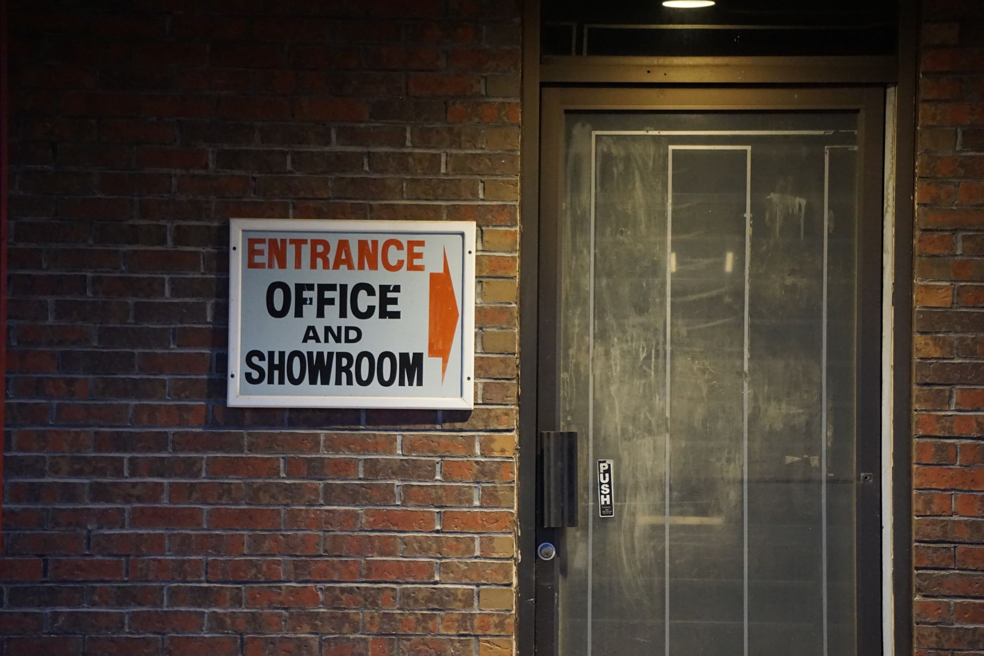 Entrance to an office and showroom with a brick wall and a push door.
