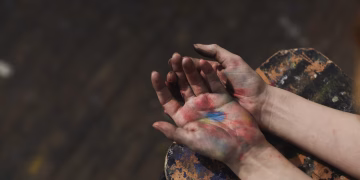 Close-up of hands covered in colorful paint, showcasing artistic creativity and expression.
