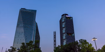 Dramatic view of Mexico City's skyline with prominent skyscrapers under a clear blue sky.