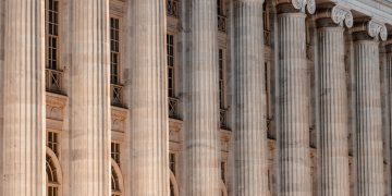 a large building with columns and a clock on the front of it
