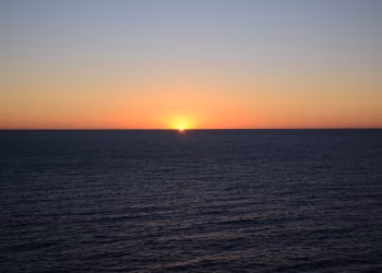 A tranquil sunset over a vast ocean horizon, showcasing vibrant colors and calm waters.