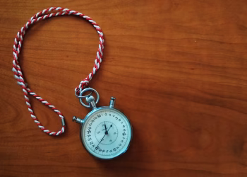 Close-up shot of an antique stopwatch with rope on wooden table.