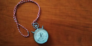 Close-up shot of an antique stopwatch with rope on wooden table.