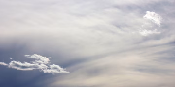 A peaceful cloudy sky with soft, wispy clouds and a calm blue gradient. Perfect background.