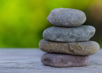 Four smooth stones stacked outdoors, symbolizing balance and tranquility.