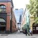 People walking in urban street with mix of historic and modern buildings.