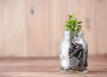 A jar filled with coins and a plant symbolizes growth in savings and investment.
