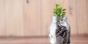 A jar filled with coins and a plant symbolizes growth in savings and investment.