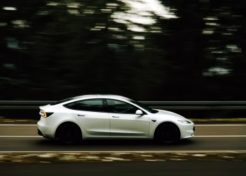 Dynamic shot of a white car in motion along a tree-lined highway capturing speed and elegance.