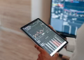 A person uses a tablet to monitor stock market trends and real-time trading graphs.