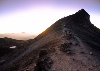 Adventurous hikers ascending a rugged mountain trail at sunrise in Mexico.