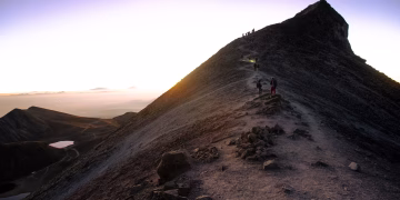 Adventurous hikers ascending a rugged mountain trail at sunrise in Mexico.