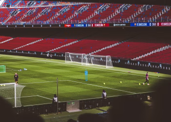 Soccer practice at a famous stadium with vibrant red seating and green field.