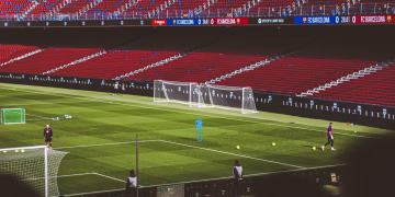 Soccer practice at a famous stadium with vibrant red seating and green field.