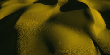 Stunning aerial view of golden sand dunes with artistic shadows and textures.