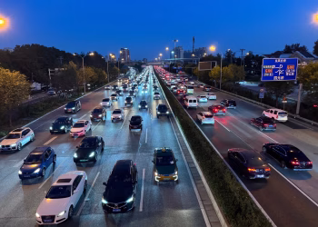 Evening view of busy traffic on a Beijing highway with illuminated city lights.