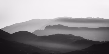 Stunning black and white mountain scene with mist creating a dramatic atmosphere.