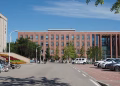A modern urban campus with parked bicycles and cars on a sunny summer day.