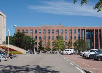 A modern urban campus with parked bicycles and cars on a sunny summer day.