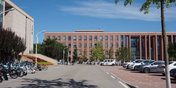 A modern urban campus with parked bicycles and cars on a sunny summer day.