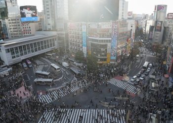 Crowded shibuya crossing with traffic and pedestrians