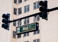 Traffic lights and Wall St sign in cityscape, symbolizing finance hub.