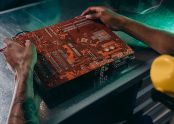Close-up of a technician working on a circuit board in an industrial setting.