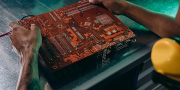 Close-up of a technician working on a circuit board in an industrial setting.