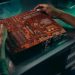 Close-up of a technician working on a circuit board in an industrial setting.