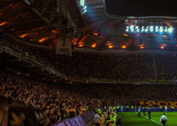 Exciting night soccer game with packed cheering fans and vibrant stadium lights.