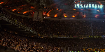 Exciting night soccer game with packed cheering fans and vibrant stadium lights.