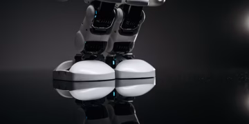 Close-up of robotic legs reflecting on a glossy surface in a studio setting.