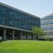 Contemporary glass office building surrounded by lush green grass in daylight.